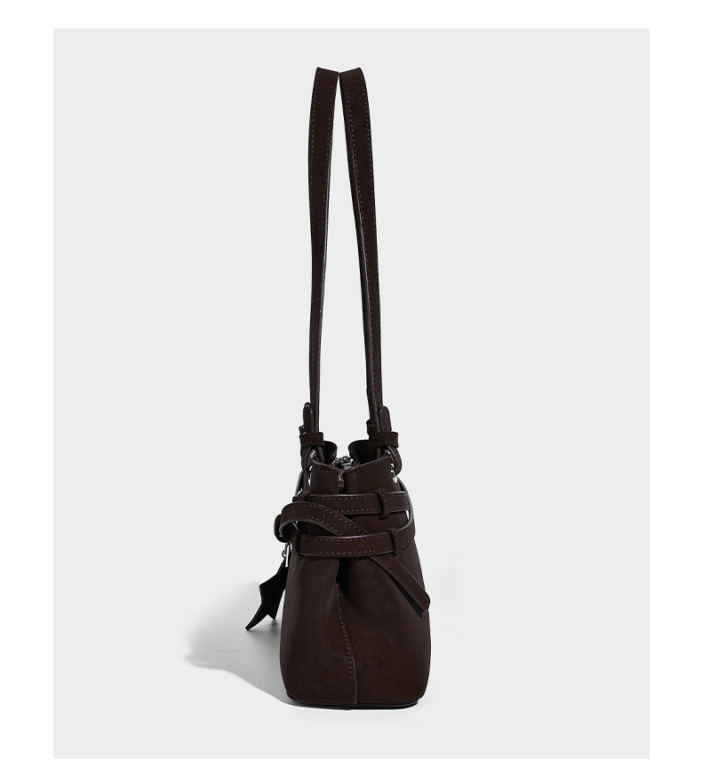 Structured trapezoid shoulder tote in dark brown matte suede-look finish with dual straps, wraparound belt bands