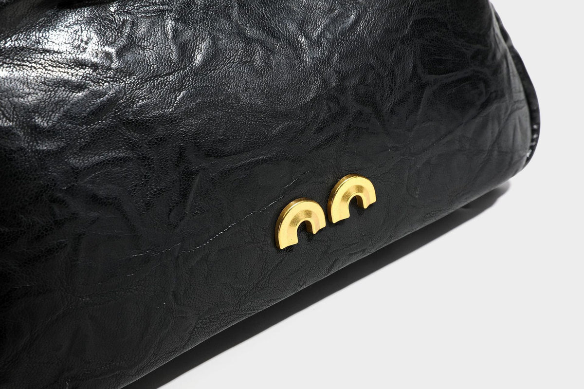 Compact black crinkled leather-look baguette shoulder bag with gold-tone arch hardware and adjustable strap, detail view 29
