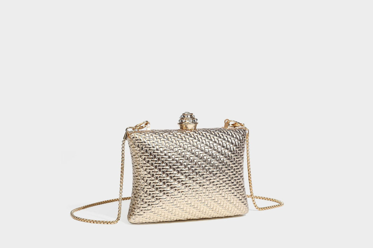 Small structured rectangular metallic woven-texture clutch bag with jeweled knob clasp and gold-tone chain strap, detail view