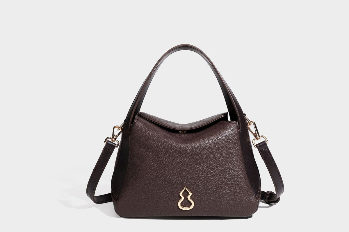 Structured pebbled leather-look shoulder bag with flap top, gold-tone emblem hardware, dual top handles, and detachable