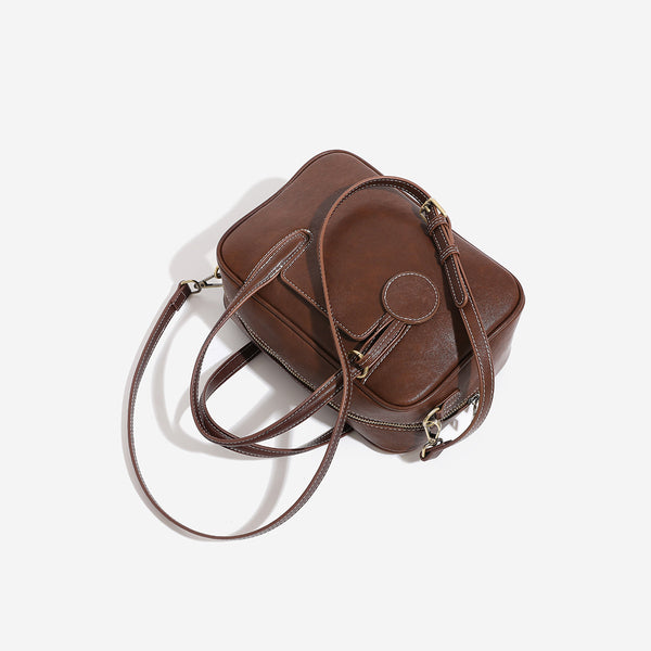 Structured boxy bowling-style tote bag in deep brown leather-look finish with dual top handles, front slip pocket, round