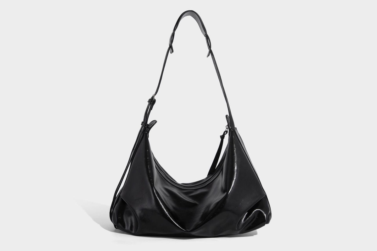 Glossy black slouchy hobo shoulder bag with zip closure, silver-tone ring hardware, and adjustable crossbody strap, detail