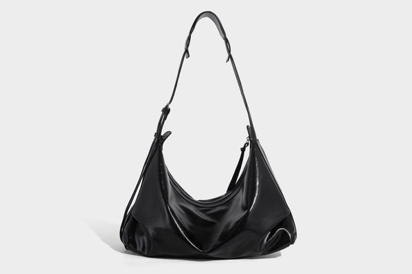Glossy black slouchy hobo shoulder bag with zip closure, silver-tone ring hardware, and adjustable crossbody strap, detail