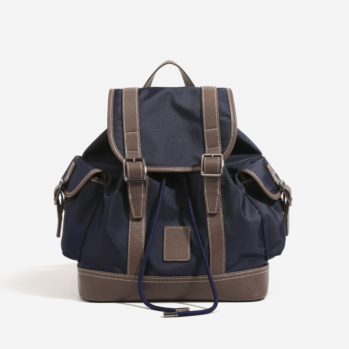 Deep navy canvas backpack with brown textured leather-look trim, drawstring flap closure, buckle-strap front detail, and