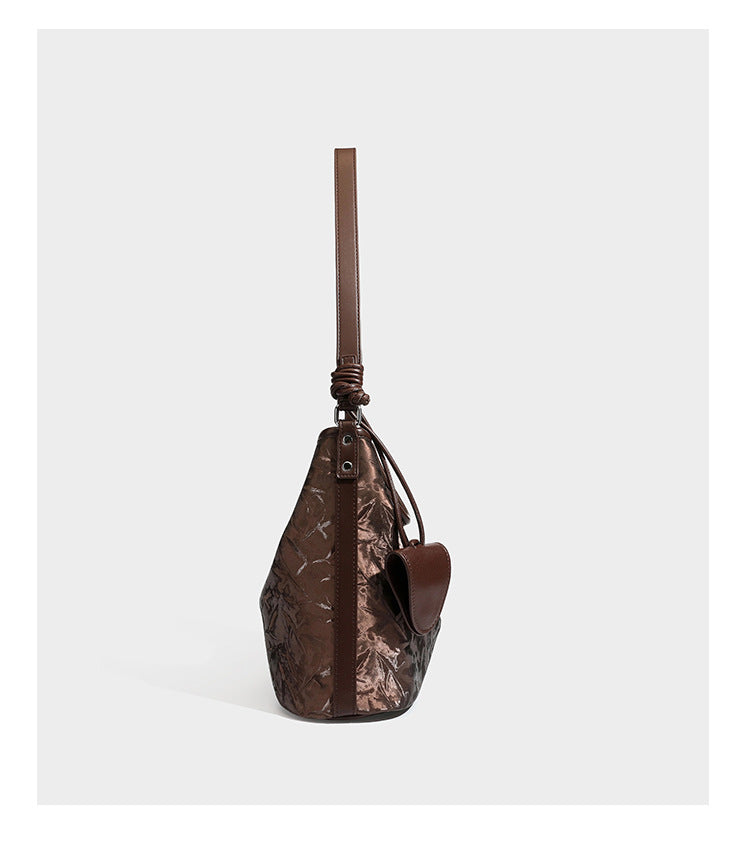 Große Hobo-Schultertasche mit Knitterglanz in Dunkelbraun, schmalem verstellbarem Riemen, geknoteten Metalldetails und seitlich angesetzter Klappe