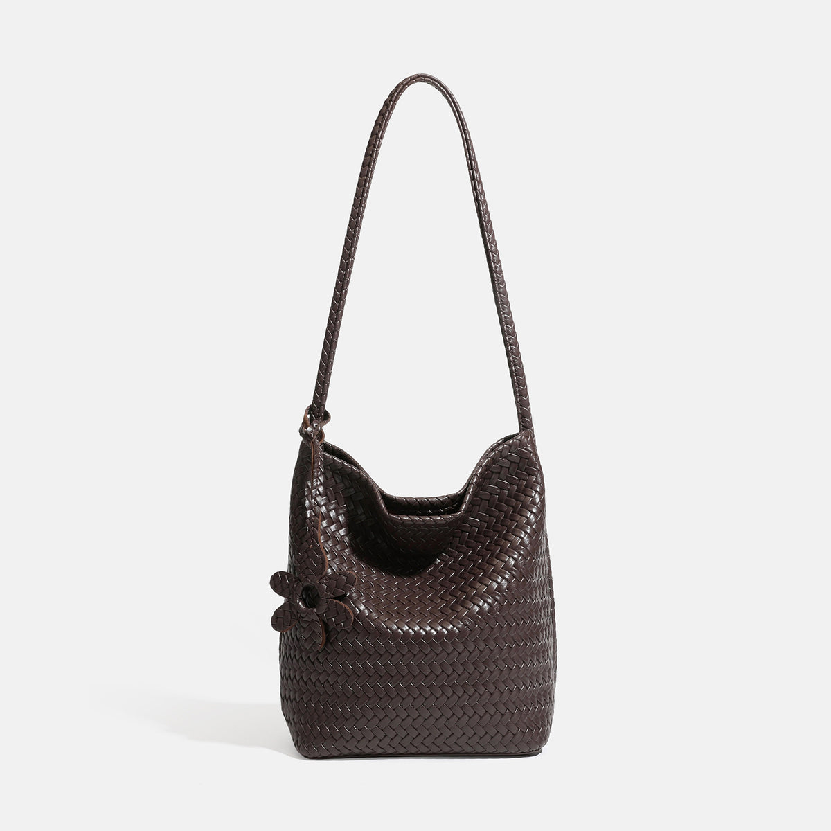 Dark brown woven leather-look bucket shoulder bag with braided strap, flower charm, and matching zip pouch, front view