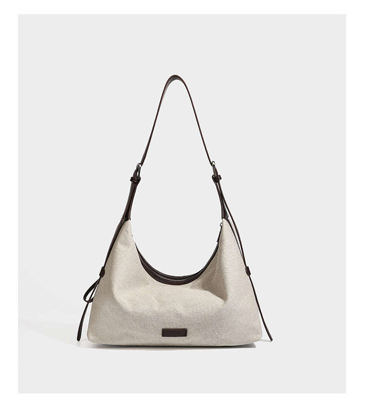 Cream canvas hobo shoulder bag with dark brown leather-look trim, zip-top closure, adjustable strap, and silver-tone