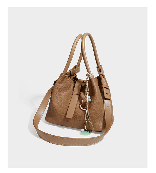 Pebbled leather-look bucket tote bag with rolled double handles, drawstring closure, braided cord charm, and detachable