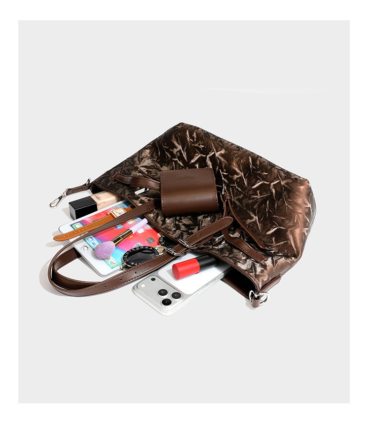 Glossy crinkled metallic-finish tote bag in brown with smooth leather-look top handles, silver-tone hardware, and attached