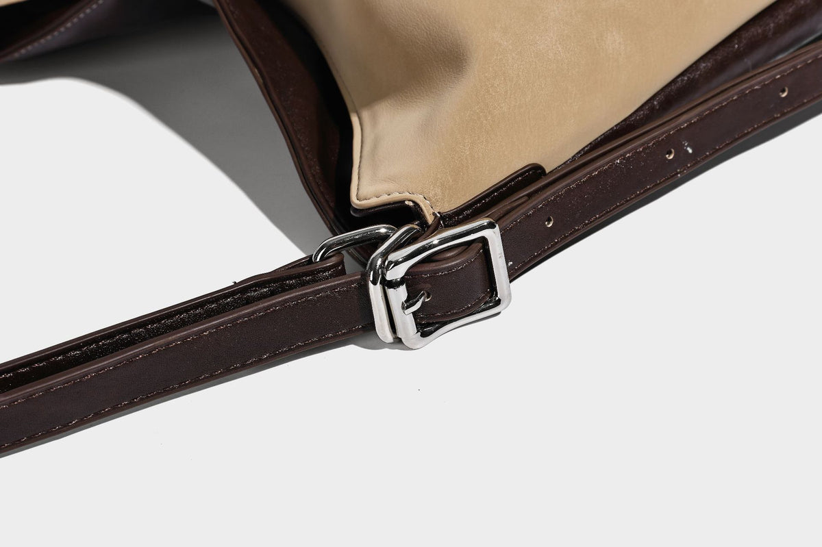 Slouchy hobo tote bag with matte leather-look finish, triangular silhouette, front zip pocket, and adjustable shoulder strap