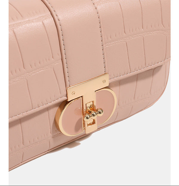 Small structured crocodile-embossed flap shoulder bag with circular gold turn-lock closure and chain-accent strap, detail