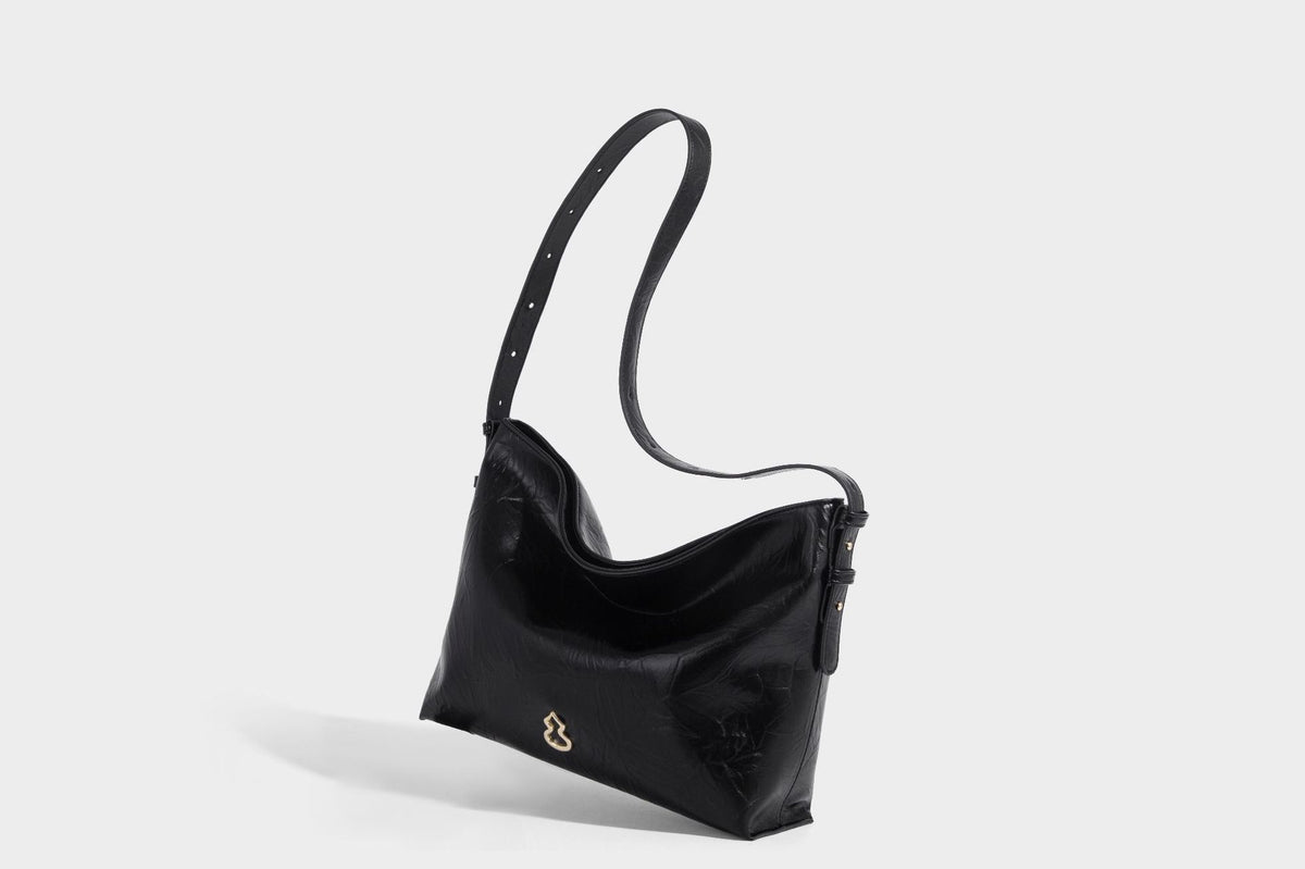Large slouchy hobo shoulder bag in glossy crinkle leather-look finish with gold-tone emblem hardware and adjustable strap