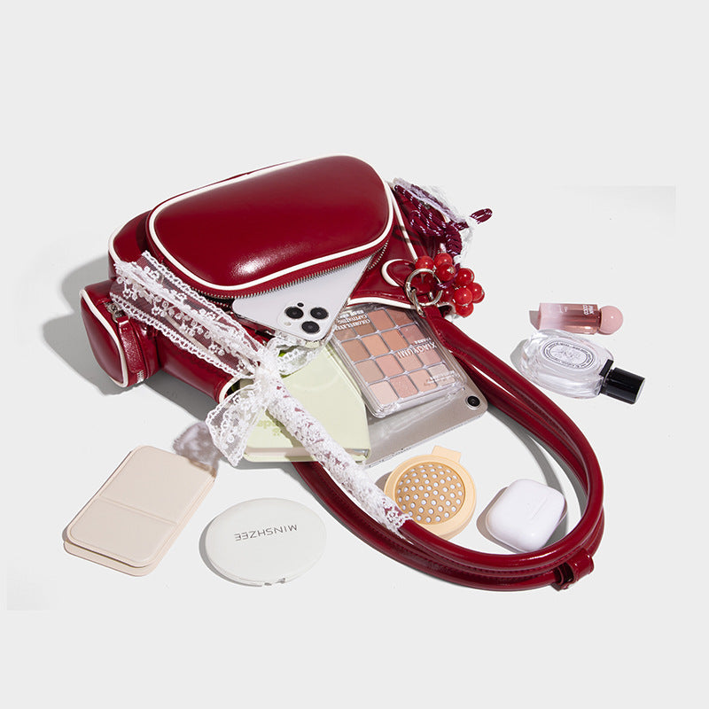 Kleine, strukturierte, glänzende Schultertasche mit weißer Paspelierung, Spitzenschleife und Anhänger mit roter Perle, seitlichen Reißverschlusstaschen und silberfarbenem
