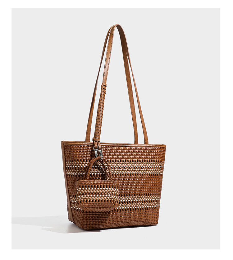Large structured woven tote bag with striped basket-weave finish, long shoulder straps, and detachable mini pouch charm