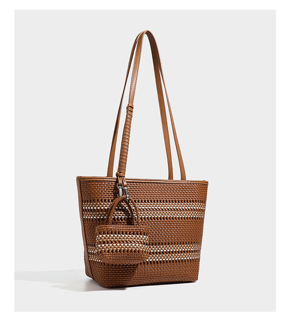 Large structured woven tote bag with striped basket-weave finish, long shoulder straps, and detachable mini pouch charm