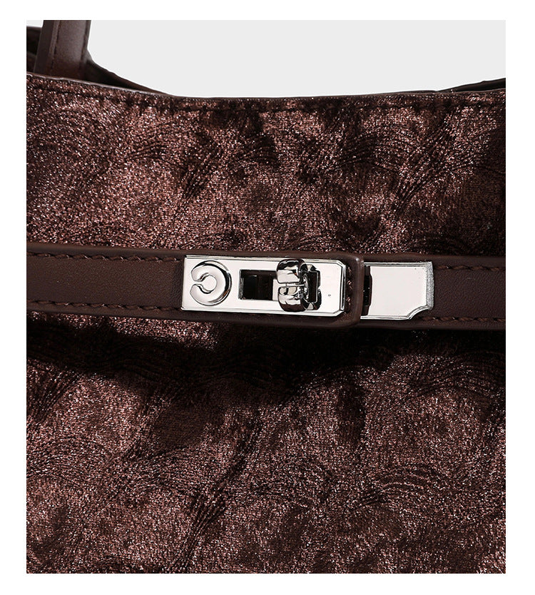 Small structured bucket satchel in embossed velvet-texture fabric with silver turn-lock hardware, rounded top handle, and
