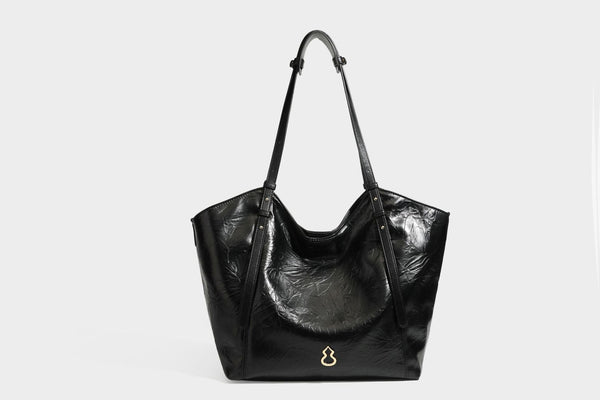 Große, glänzende Tote-Bag aus schwarzem Lederimitat mit geknitterter Optik, lässig fallender Trapezsilhouette, zwei Schulterriemen und goldfarbenen