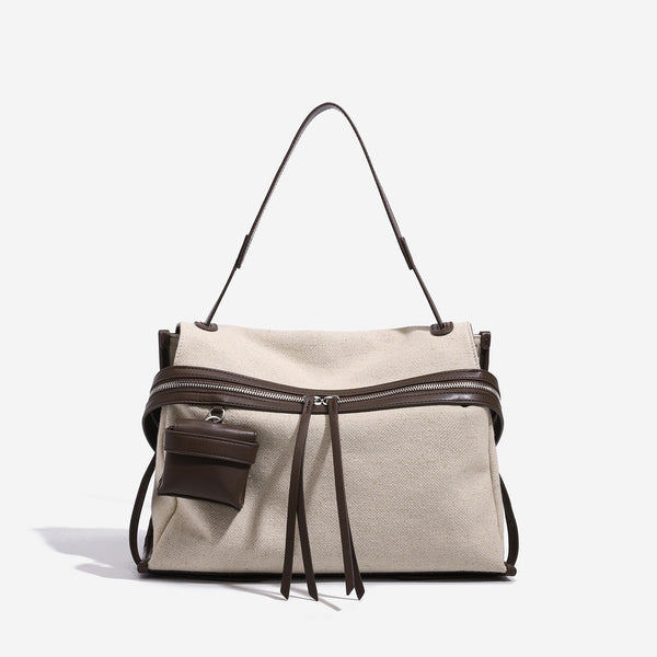 Cream canvas messenger shoulder bag with tan leather-look trim, dual zippers, tassel pulls, and attached mini front pouch