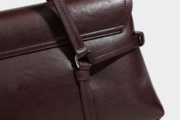 Strukturierte rechteckige Schultertasche mit Überschlagverschluss, vorderem Schnallengurt-Detail und ringförmigen Beschlägen in