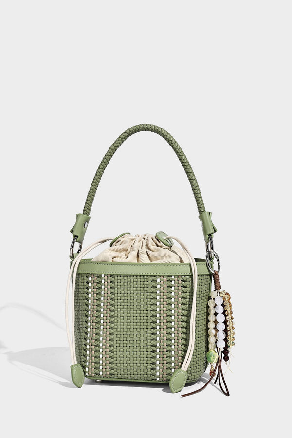 Small woven bucket bag with drawstring top, braided handle, detachable crossbody strap, and silver-tone ring hardware, detail