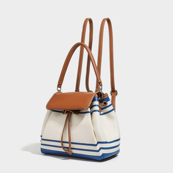 Cream canvas bucket bag with blue horizontal stripes, tan leather-look flap and trim, drawstring closure, silver-tone, detail