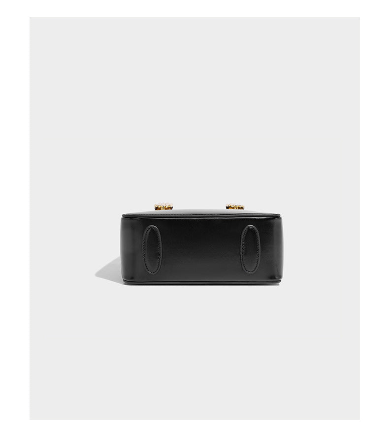Kleine, strukturierte, kastenförmige Henkeltasche mit goldfarbenem, handförmigem Metallbeschlag in schwarzer Lederoptik mit abnehmbarem Detail