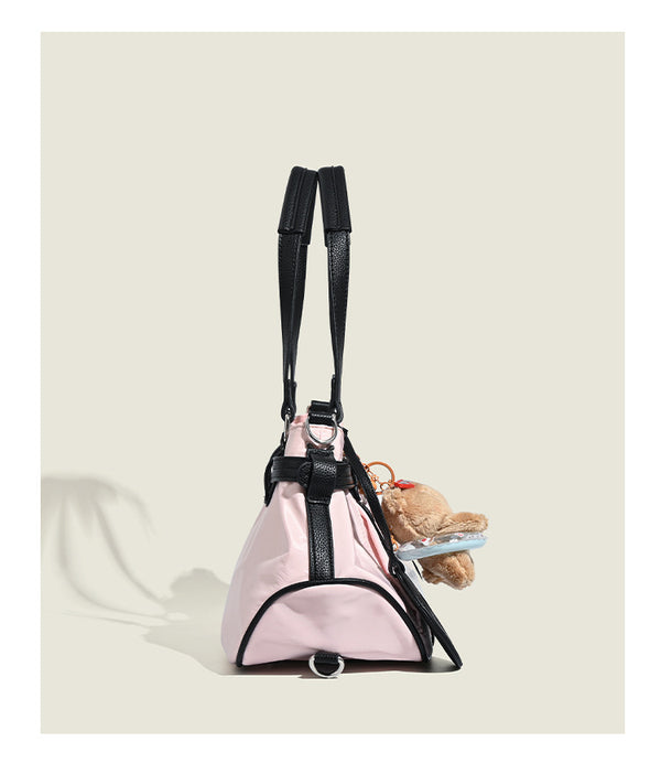 Pale pink nylon tote bag with black leather-look trim, double top handles, side zip pocket, and detachable crossbody strap