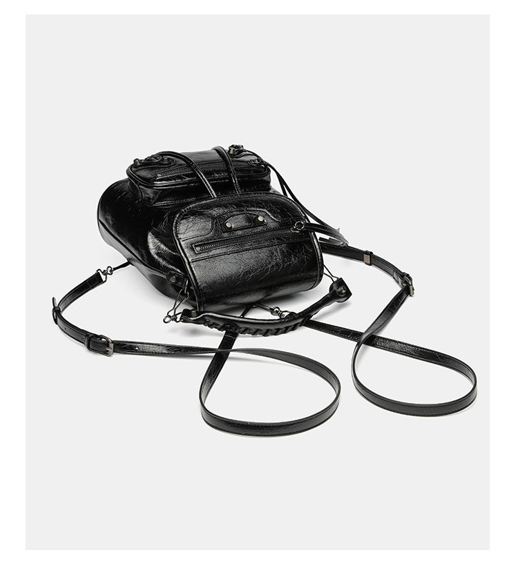 Small structured glossy leather-look convertible backpack handbag in black with flap closure, front zip pockets, metal stud