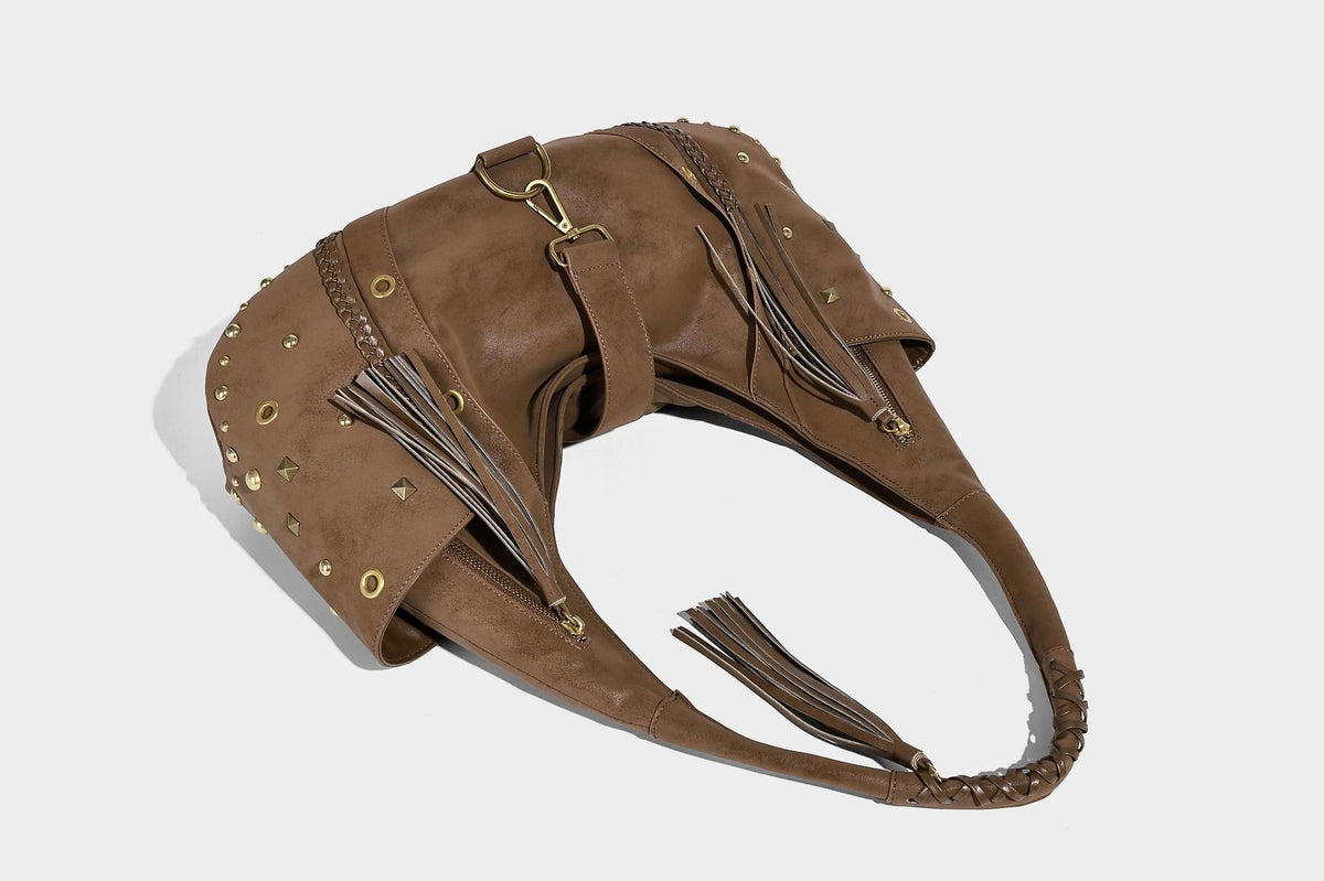 Slouchy crescent hobo bag in matte brown suede-like finish with gold-tone studs, grommets, braided top handle, tassel side