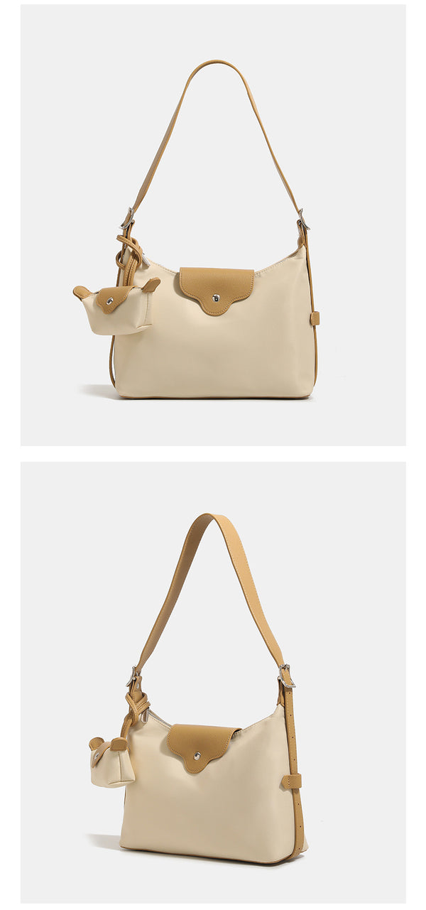Slouchy hobo shoulder bag in smooth fabric with leather-look tan trim, zip-top closure, adjustable strap, and detachable