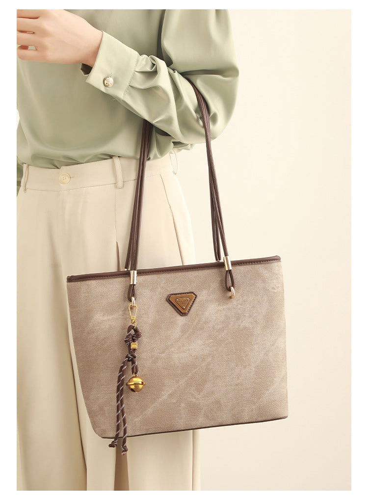Große, strukturierte Tote-Bag mit offenem Oberteil in Creme, dunkelbrauner Borte in Lederoptik, zwei Schulterriemen und dreieckigem Logo-Badge