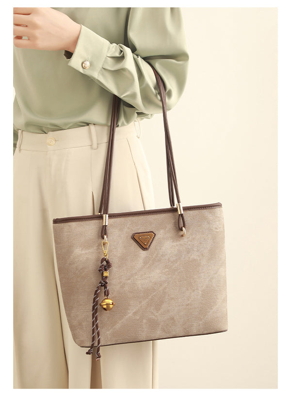 Große, strukturierte Tote-Bag mit offenem Oberteil in Creme, dunkelbrauner Borte in Lederoptik, zwei Schulterriemen und dreieckigem Logo-Badge
