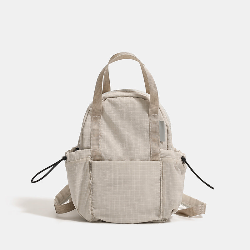 Small rounded mini backpack handbag in matte ripstop-texture fabric with top webbing handle, front pocket, side drawstring