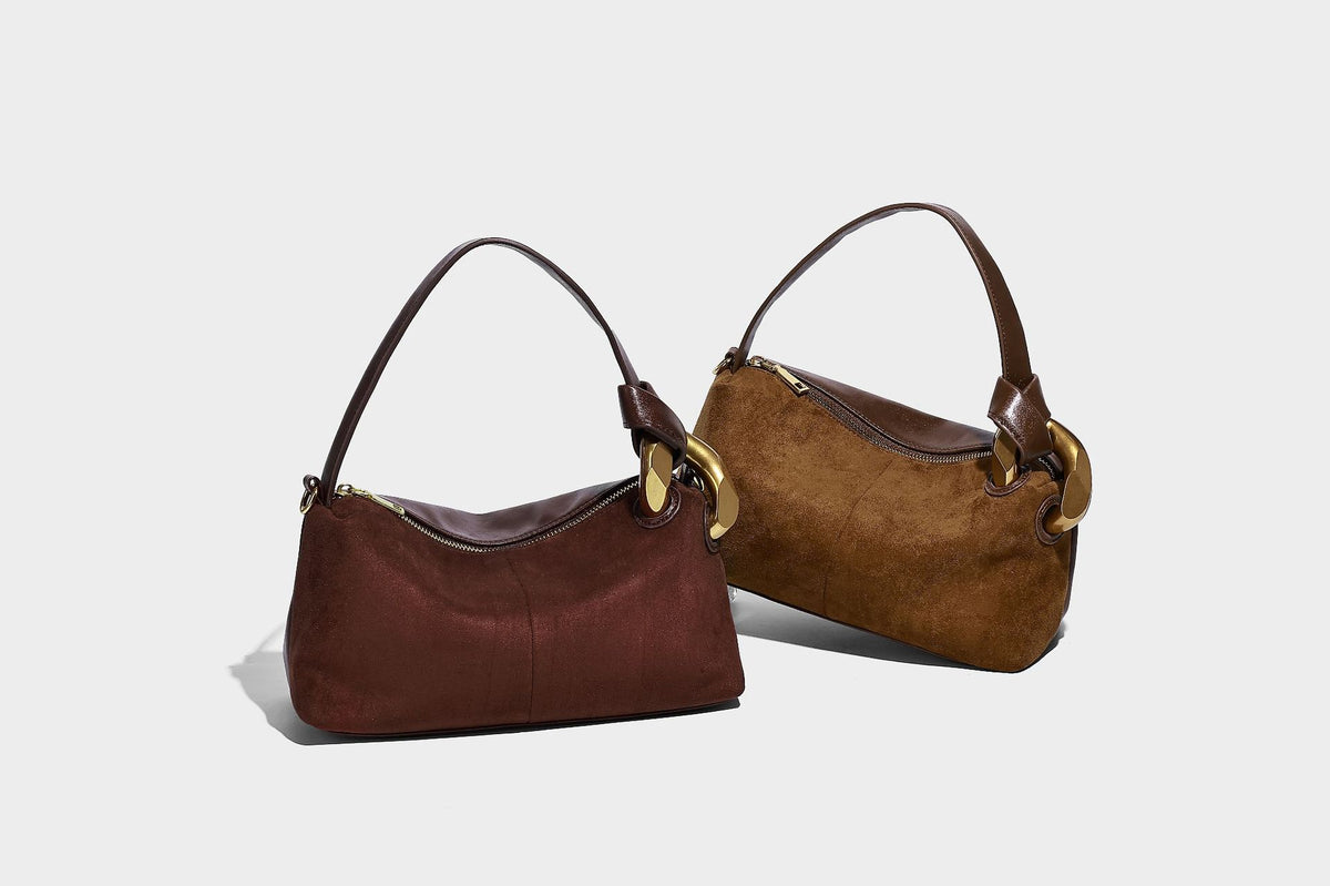 Kompakte Boston-Schultertasche in warmem Braun in Wildlederoptik mit glattem dunkelbraunem Besatz, übergroßen goldfarbenen Ringelementen und Reißverschluss oben