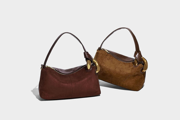 Kompakte Boston-Schultertasche in warmem Braun in Wildlederoptik mit glattem dunkelbraunem Besatz, übergroßen goldfarbenen Ringelementen und Reißverschluss oben