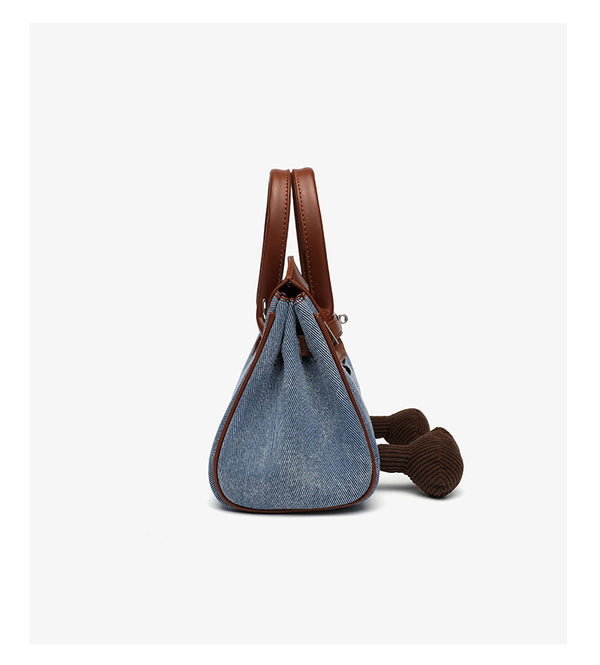 Small structured trapezoid satchel bag with smiling face motif, pom-pom accents, brown leather-look trim, silver-tone, detail