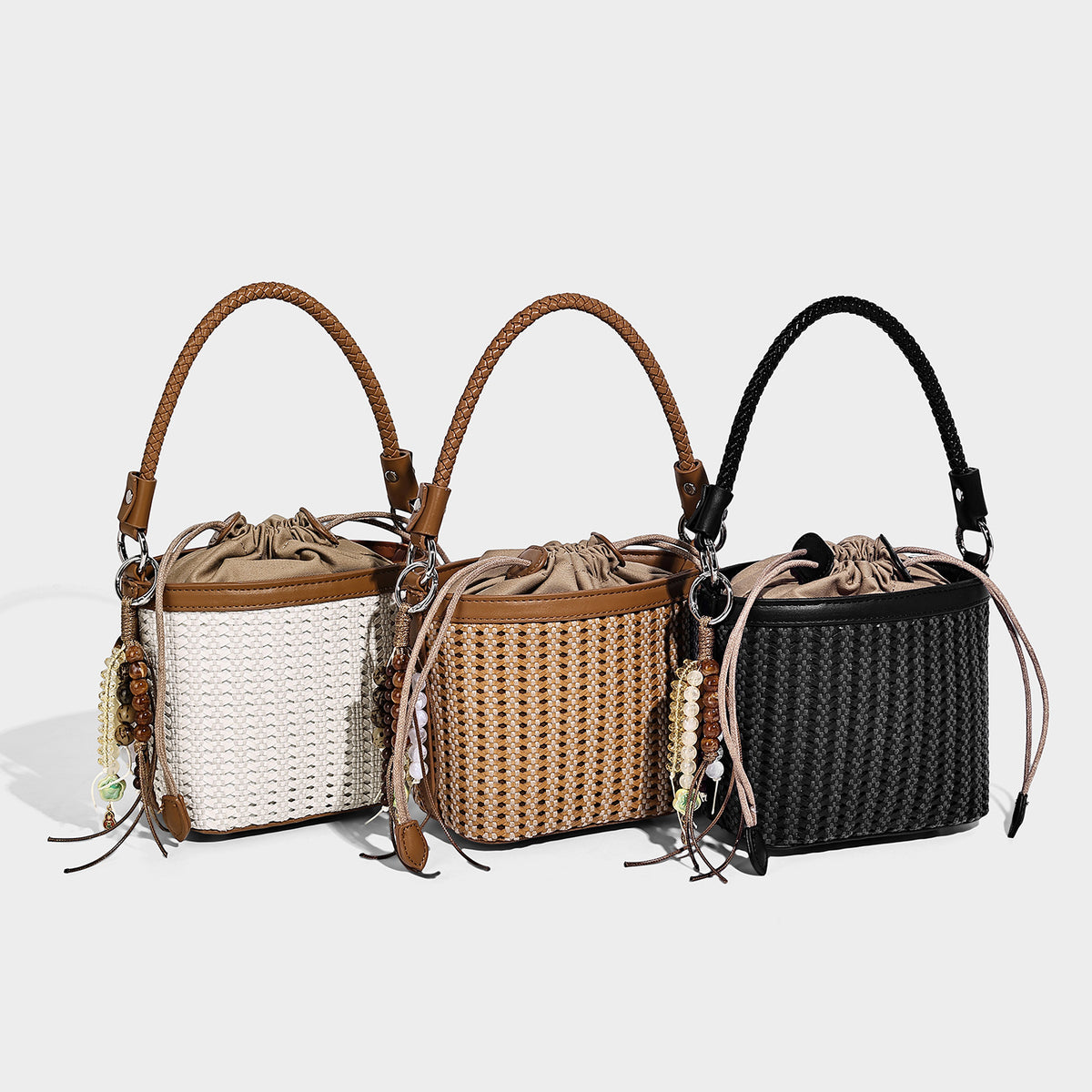 Small woven bucket bag with drawstring top, braided handle, leather-look tan trim, and bead charm tassel, detail view 2