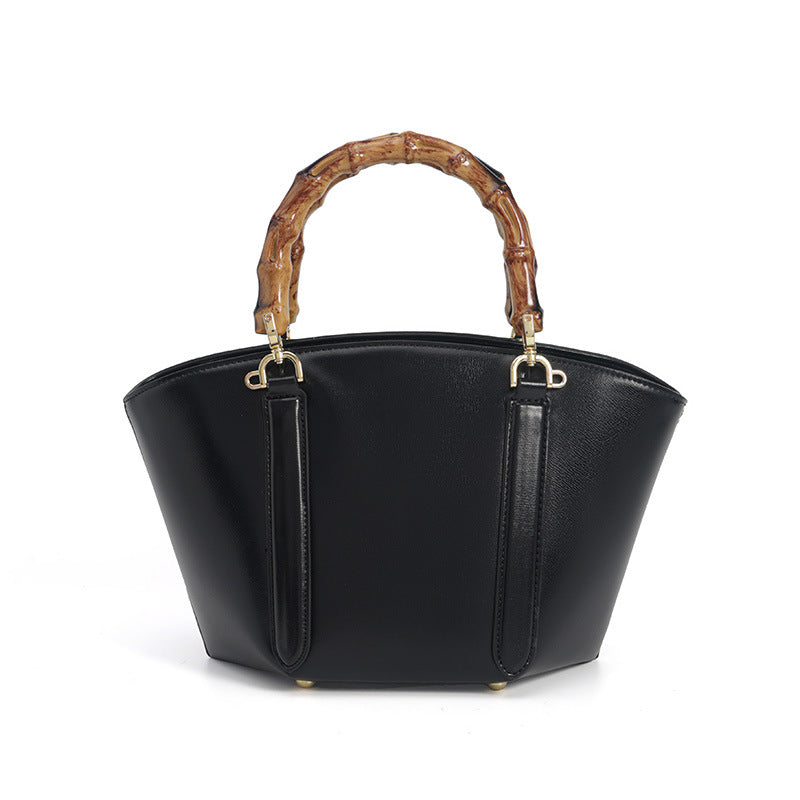 Structured trapezoid handbag with segmented bamboo top handle, smooth leather-look finish, gold-tone hardware, and vertical