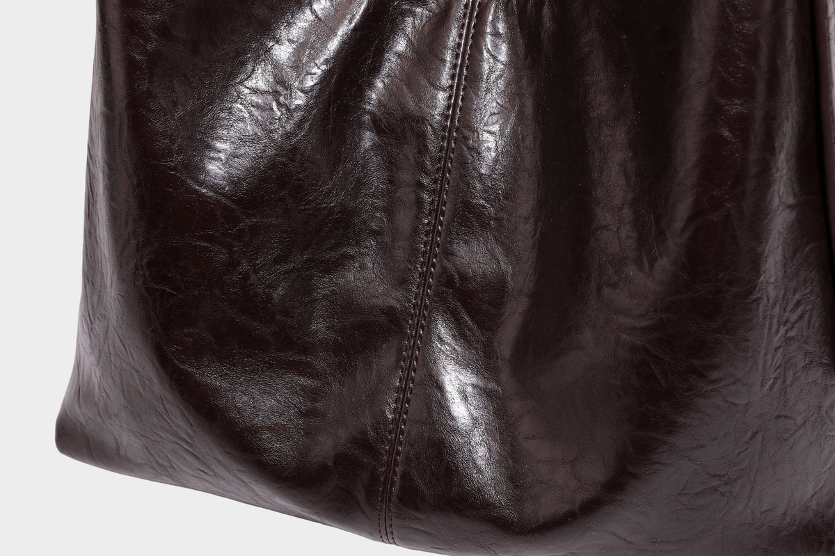 Große dunkelbraune, glänzende, geknautschte Hobo-Schultertasche mit Reißverschluss, goldfarbenen Metalldetails, verstellbarem Trageriemen und Hellblau