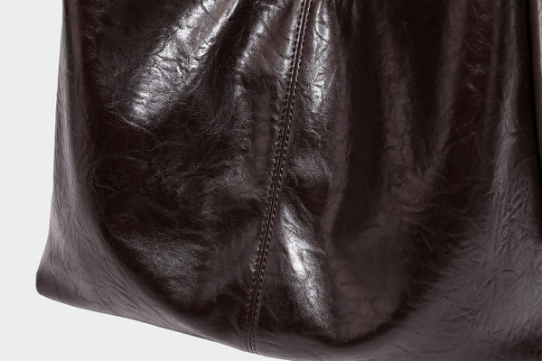 Große dunkelbraune, glänzende, geknautschte Hobo-Schultertasche mit Reißverschluss, goldfarbenen Metalldetails, verstellbarem Trageriemen und Hellblau