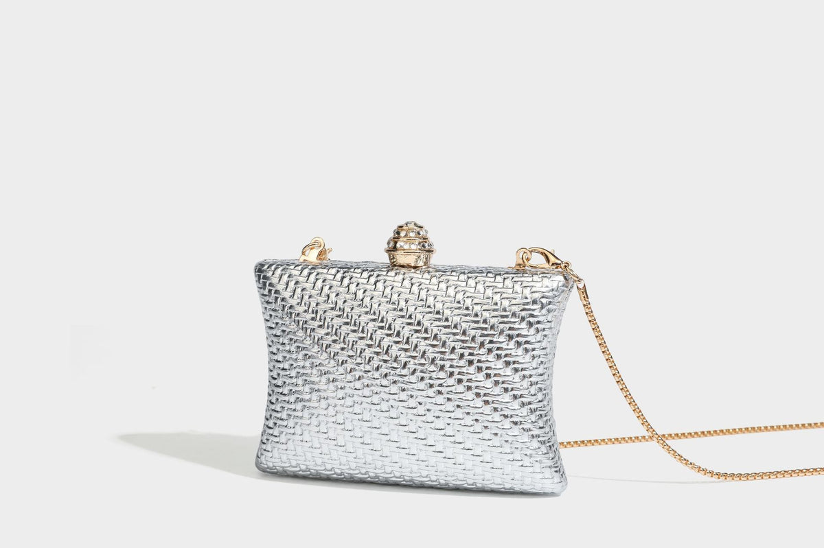 Small structured rectangular metallic woven-texture clutch bag with jeweled knob clasp and gold-tone chain strap, detail view