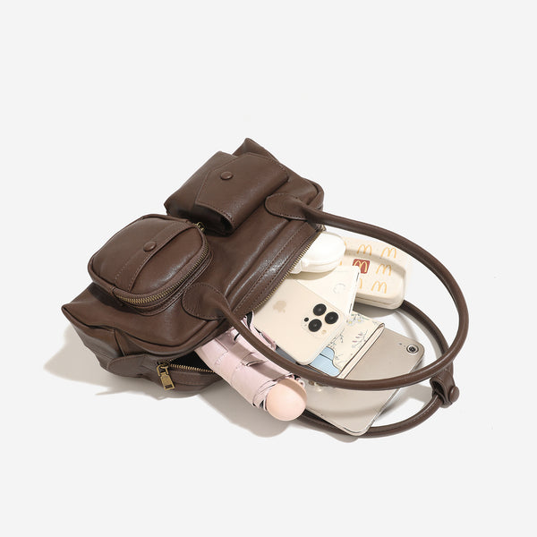 Structured matte leather-look bowling bag with snap-flap and zip front pockets, looped top handles, and antique gold-tone