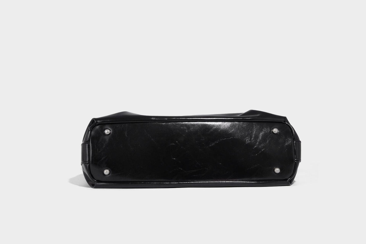 Glossy black slouchy hobo shoulder bag with zip closure, silver-tone ring hardware, and adjustable crossbody strap, detail