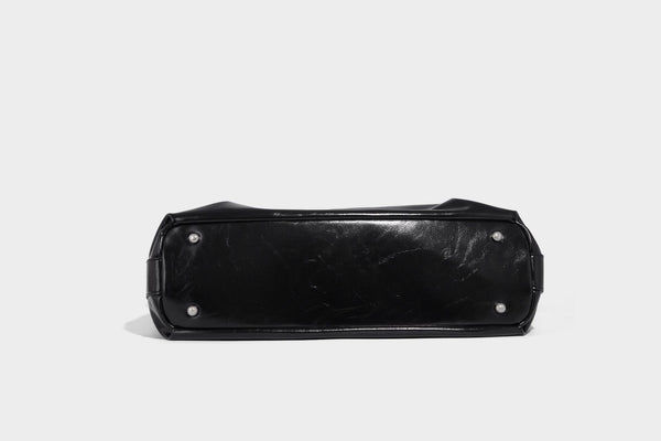 Glossy black slouchy hobo shoulder bag with zip closure, silver-tone ring hardware, and adjustable crossbody strap, detail