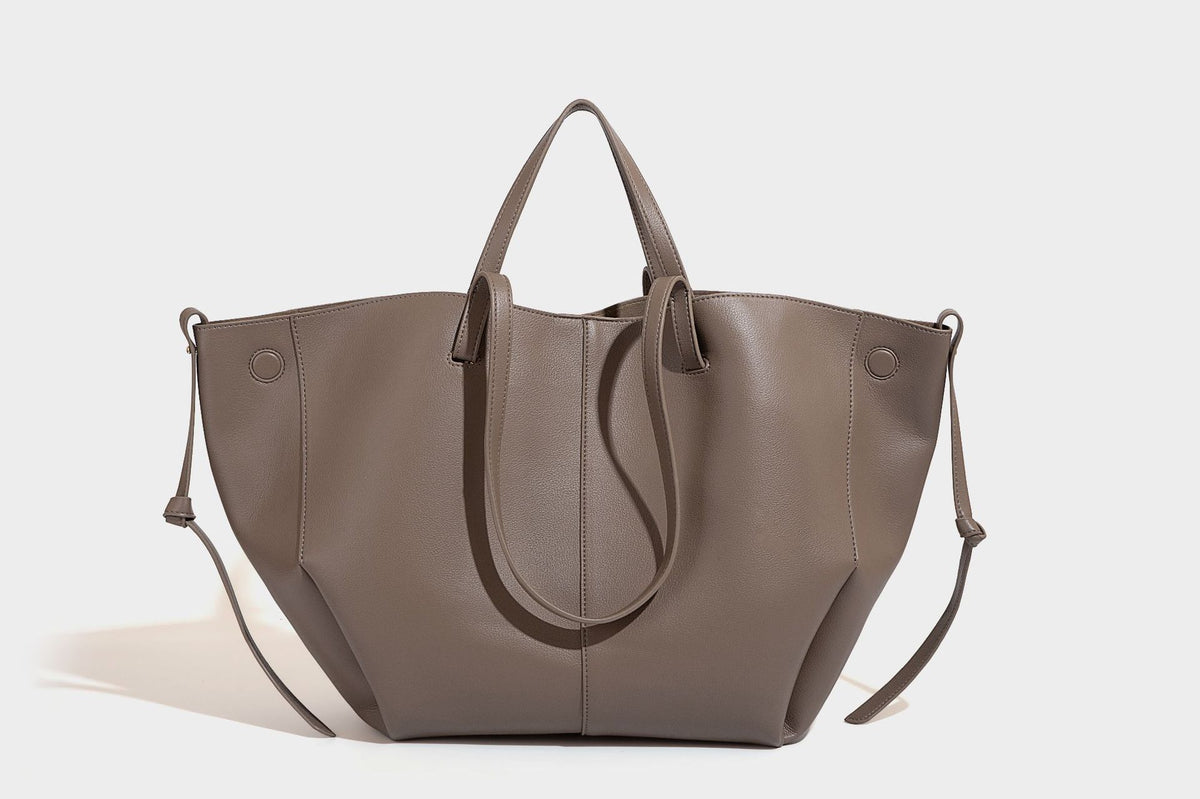 Große, formstabile trapezförmige Tote-Bag aus braunem Lederimitat mit genarbter Oberfläche, zwei Tragegriffen und seitlichen Bindebändern, Detail