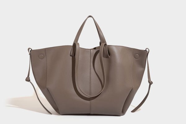 Große, formstabile trapezförmige Tote-Bag aus braunem Lederimitat mit genarbter Oberfläche, zwei Tragegriffen und seitlichen Bindebändern, Detail