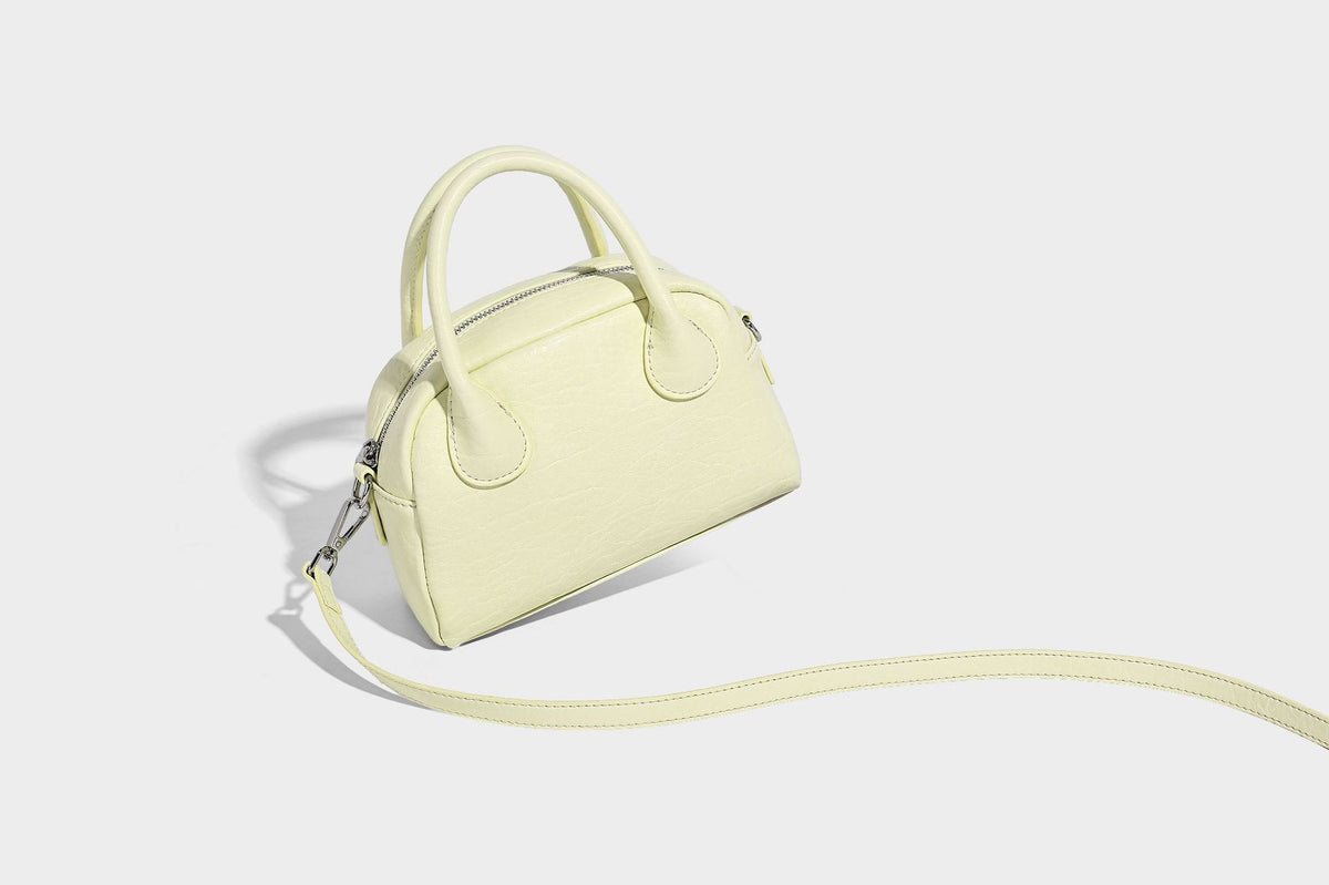 Mini-Tasche mit strukturierter Kuppelform und Tragegriff, in Pastellgelb mit genarbter Lederoptik, silberfarbenen Metallbeschlägen und abnehmbarem