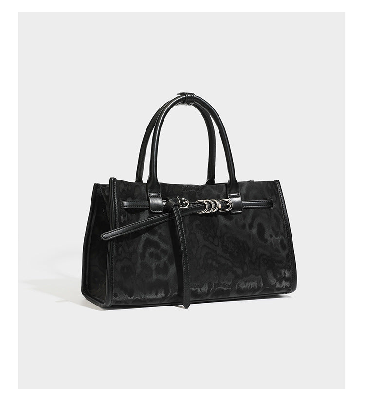 Structured leopard-print tote bag with glossy satin-like finish, dual rounded top handles, silver buckle-and-ring front