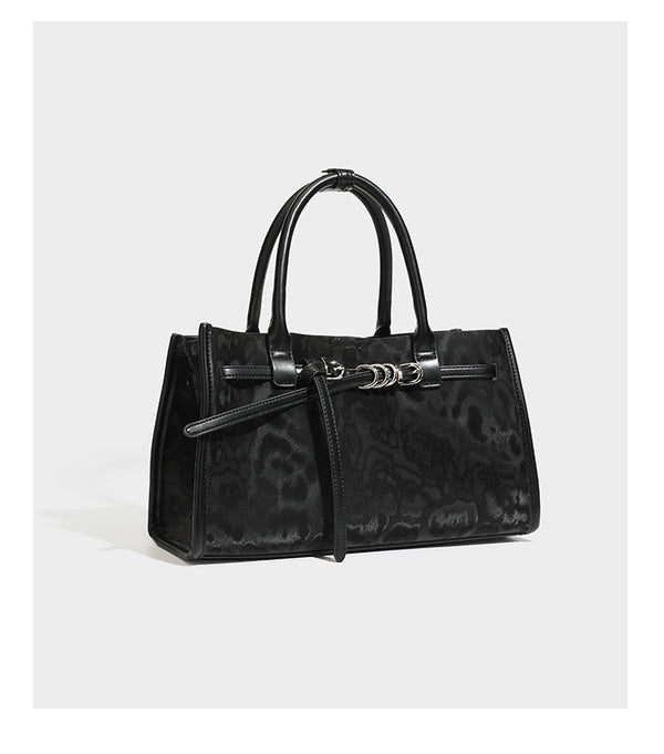 Structured leopard-print tote bag with glossy satin-like finish, dual rounded top handles, silver buckle-and-ring front