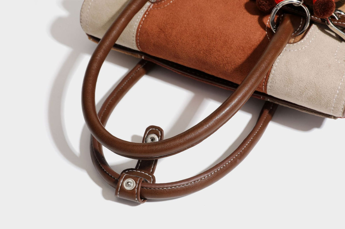 Structured color-block satchel bag in brown, rust, beige, and taupe suede-look panels with white topstitching, front buckle